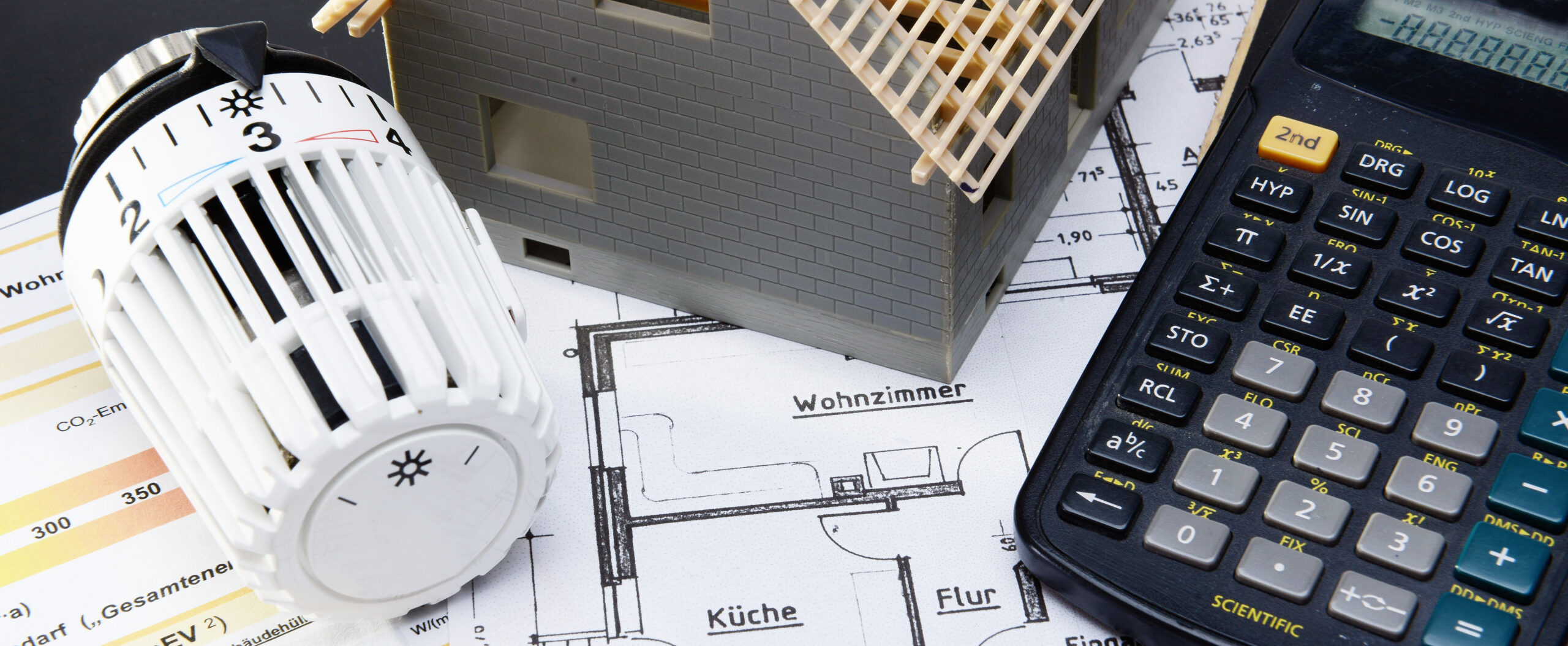 Symbolbild von einem Heizungsthermostat und einem Taschenrechner