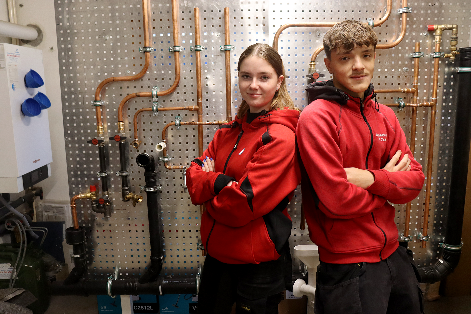 Unsere Auszubildenden Emma und Elham vor einer Montagewand zu Lehrzwecken
